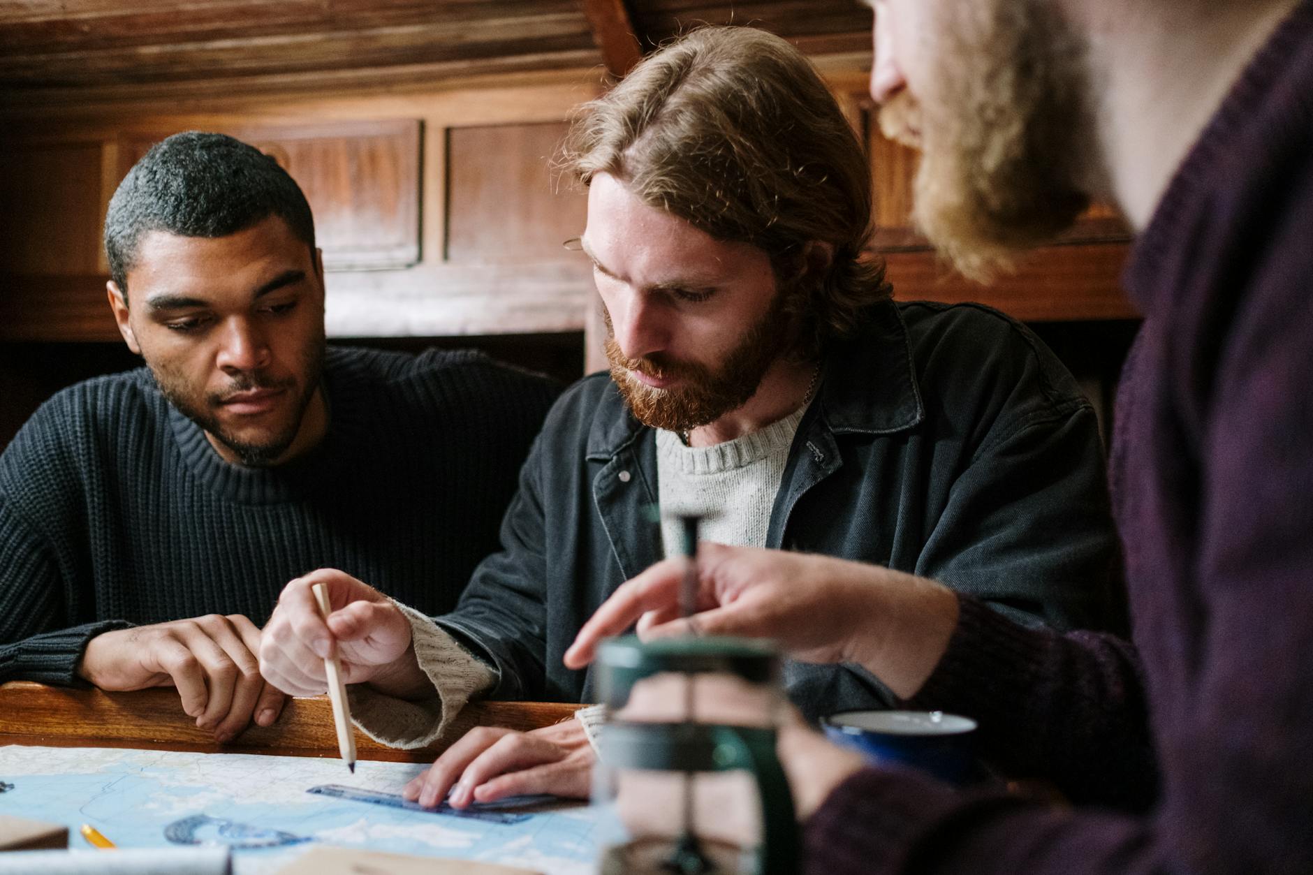 A group of young men engaged in planning a nautical adventure indoors using a detailed map.