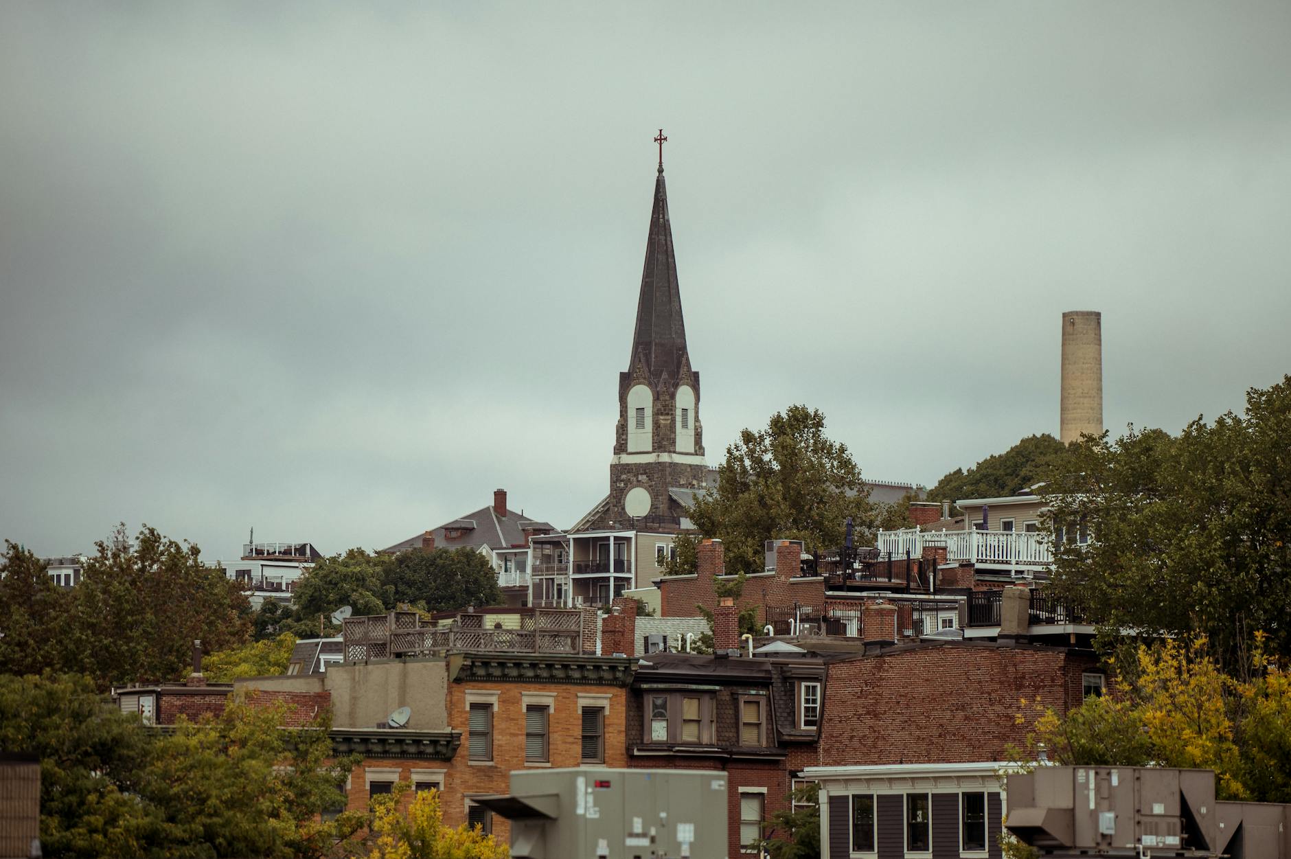 A picturesque view of Saint Francis de Sales Church spire in Charlestown amidst urban rooftops.