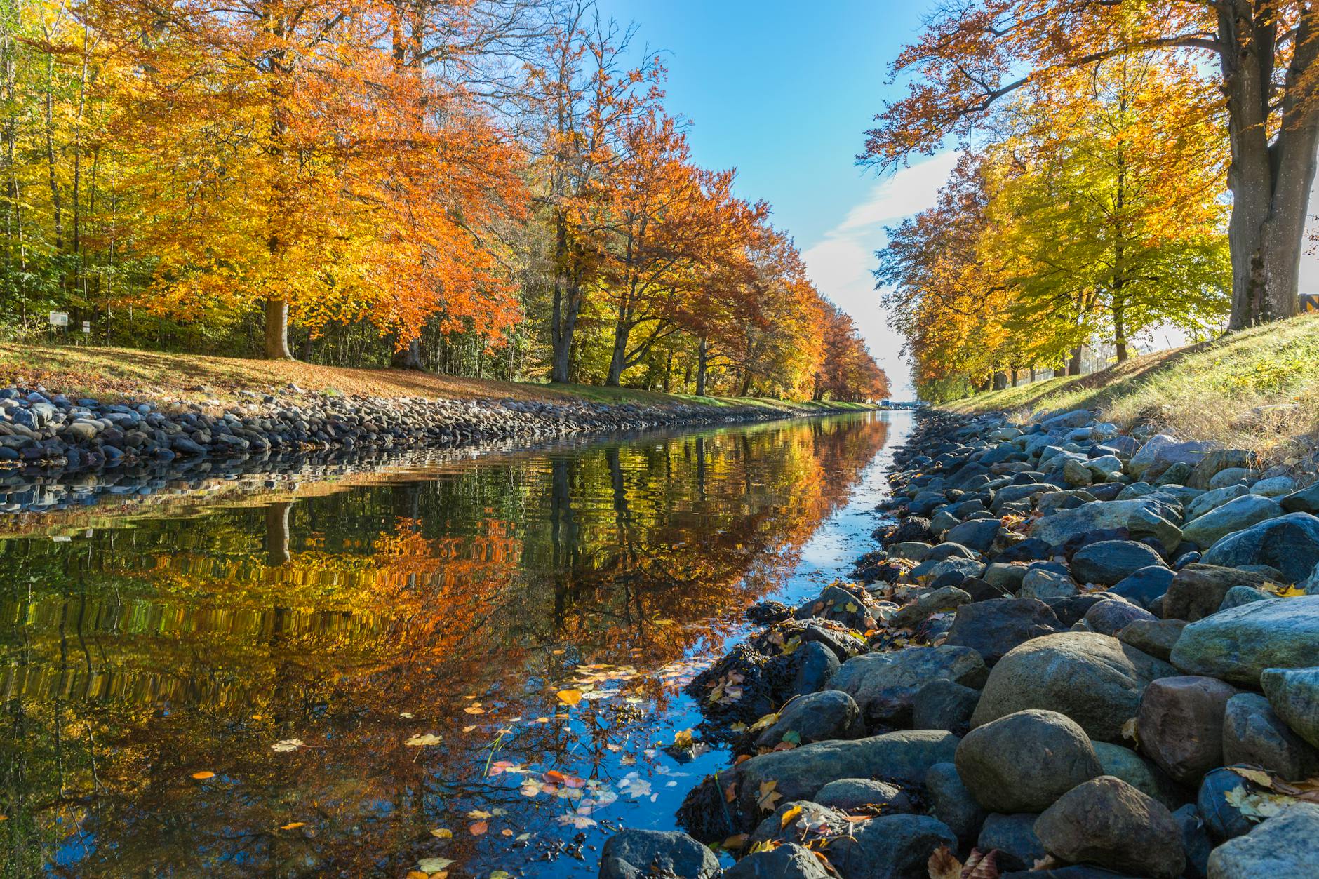 A scenic canal in Horten, Norway, with vibrant autumn foliage reflecting in the water.