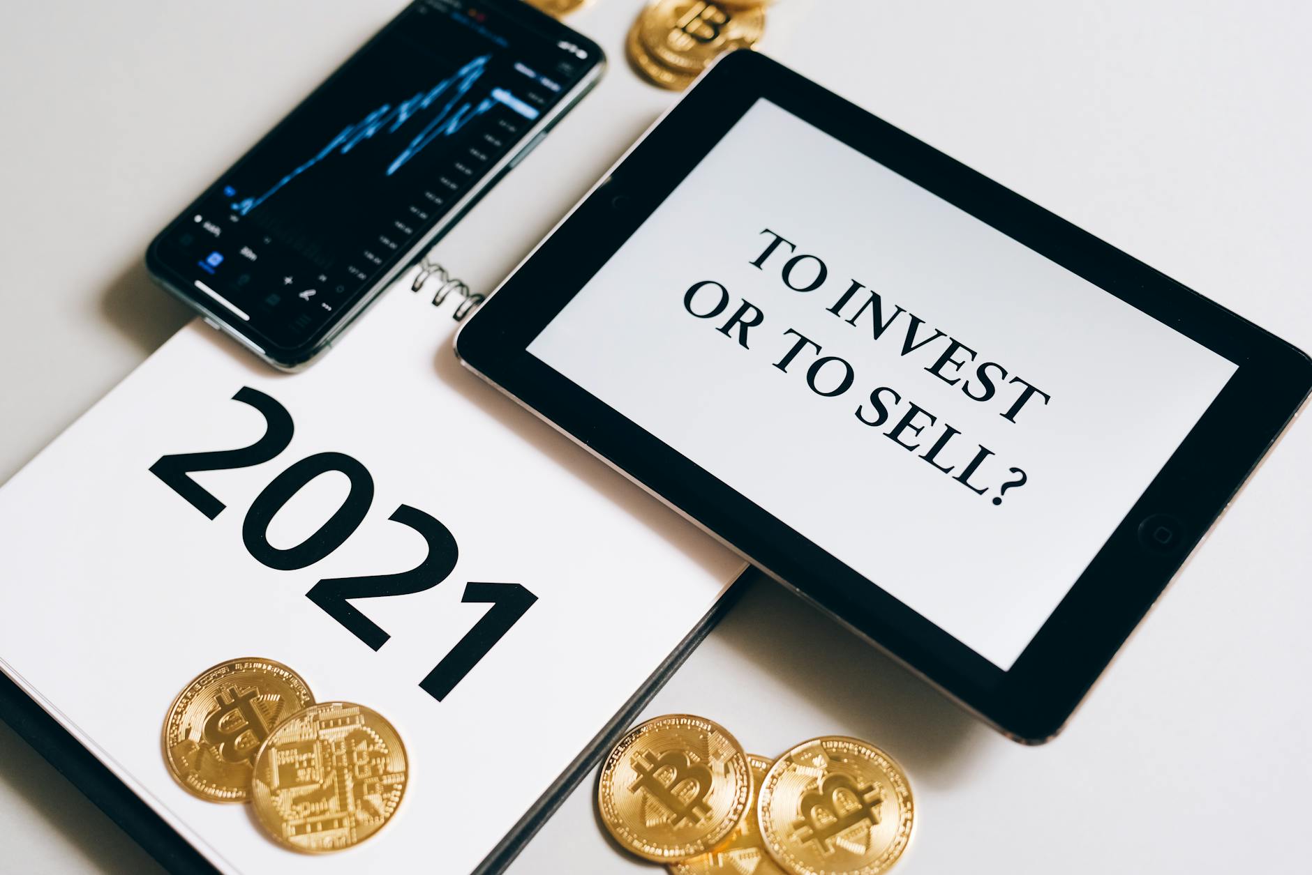 Bitcoin and investment strategy visualized with smartphone, tablet, and coins.