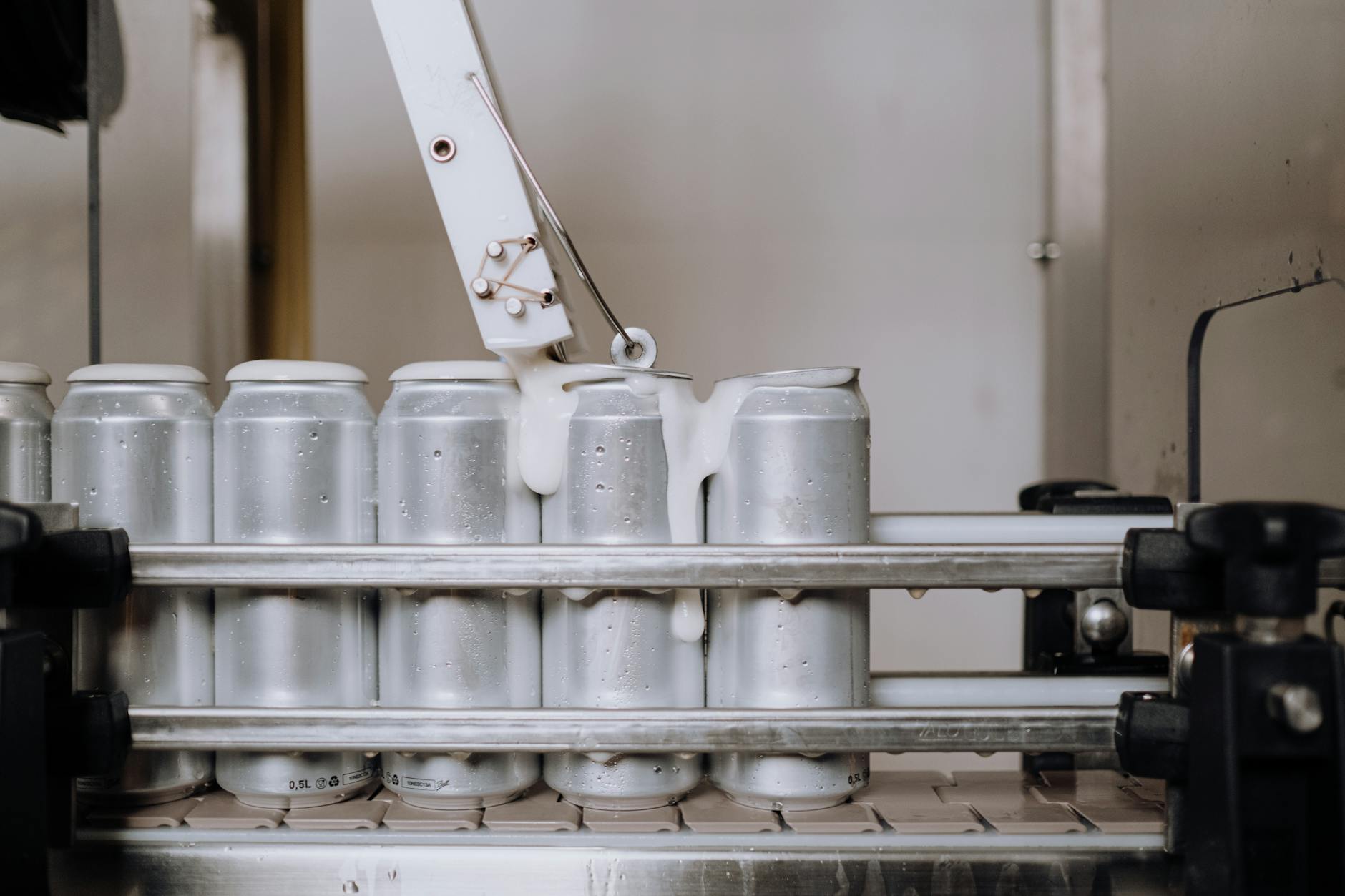 Close-up of aluminum cans being filled in an automated brewery assembly line.