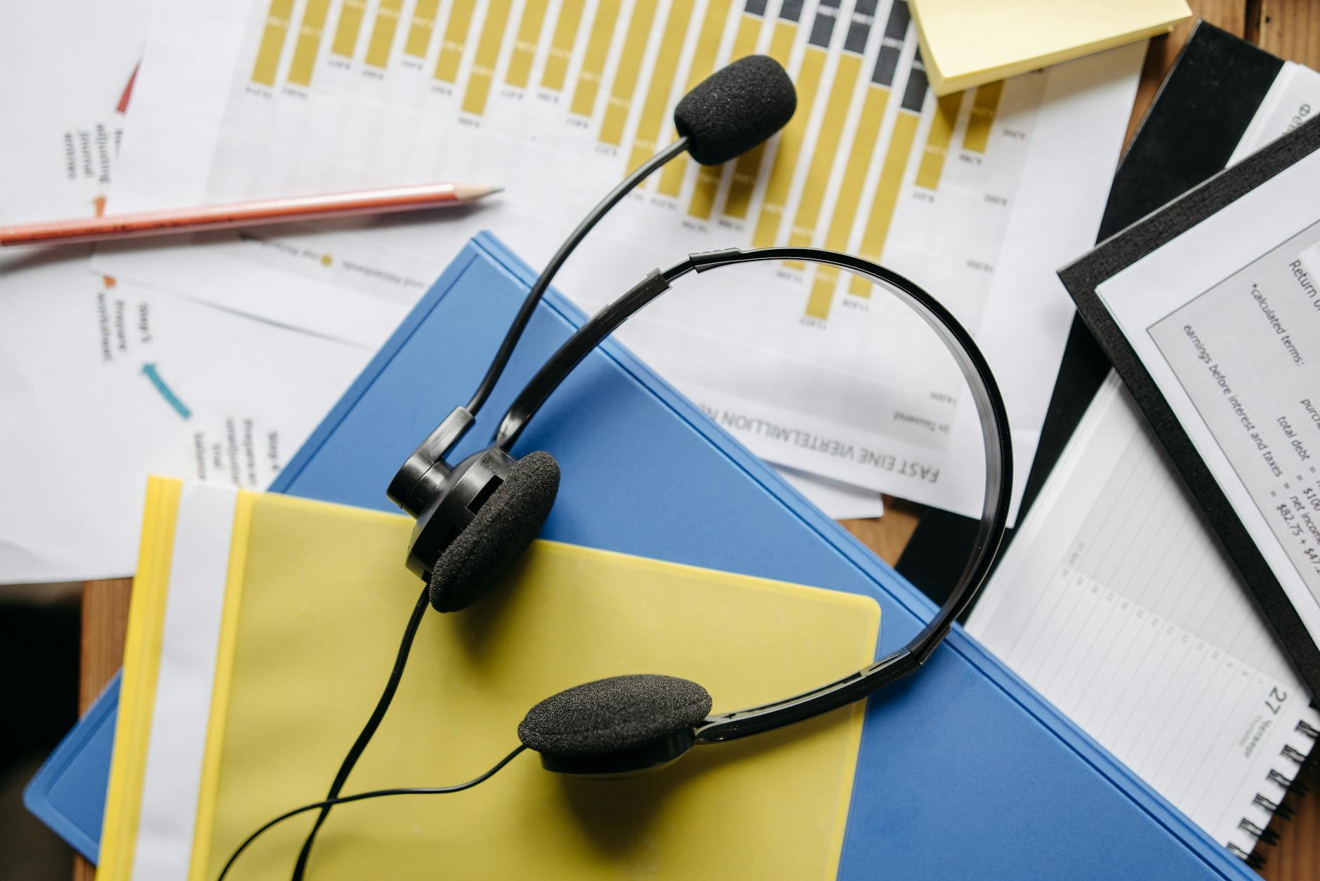 Close-up of an office desk with headset, charts, and documents showcasing customer service support.