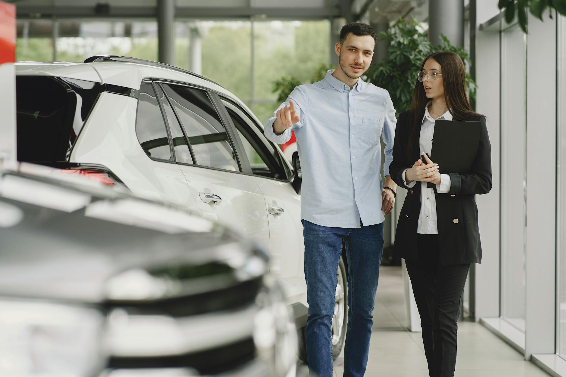 Customer and salesperson discussing a vehicle inside a modern car dealership showroom.