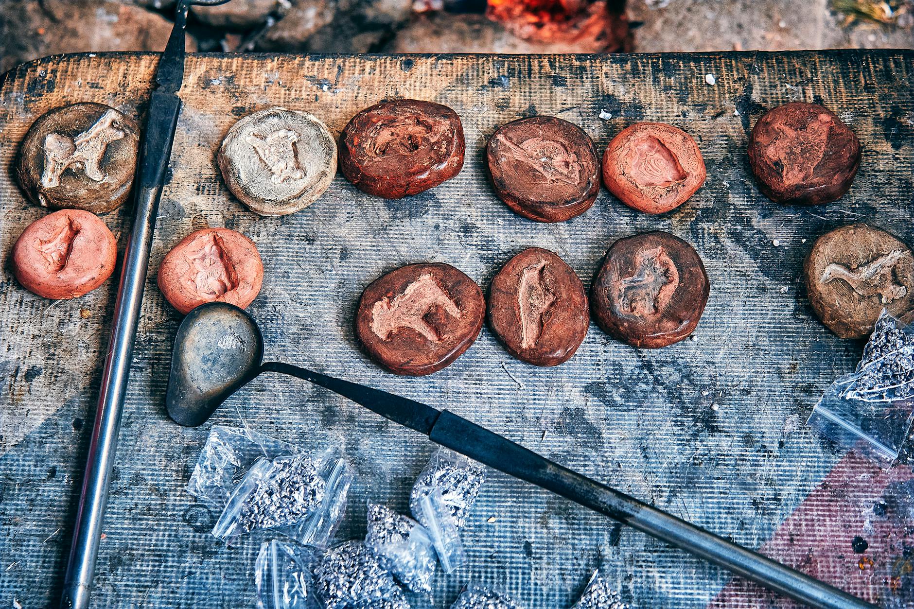 Detailed view of a craft workshop table with metal casting molds and tools highlighting an artisanal process.