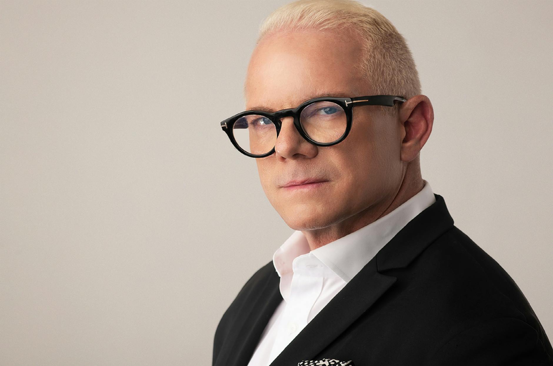 Elegant headshot of a blonde adult man wearing eyeglasses and a suit, perfect for corporate or fashion use.