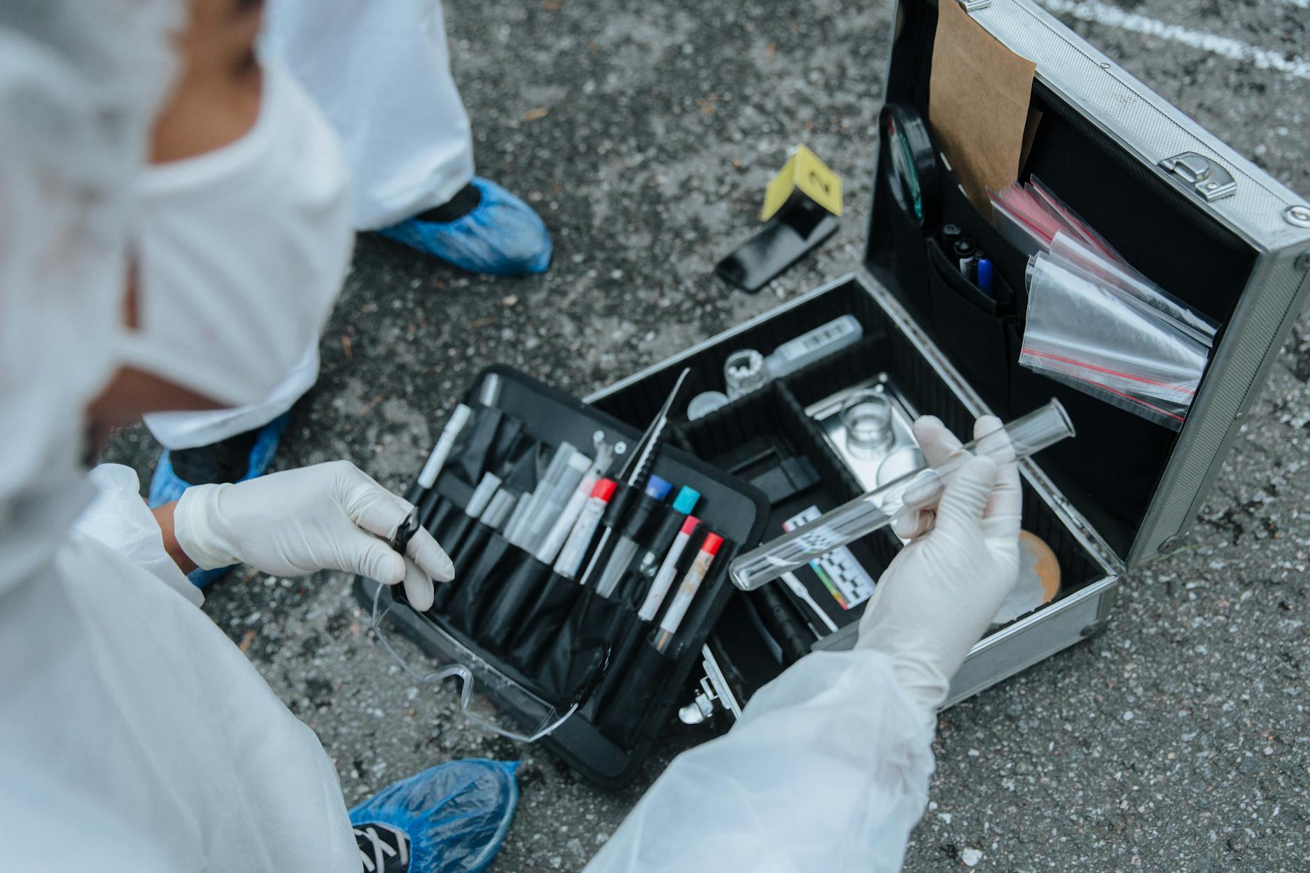 Forensic expert examining evidence with tools at a crime scene investigation outdoors.