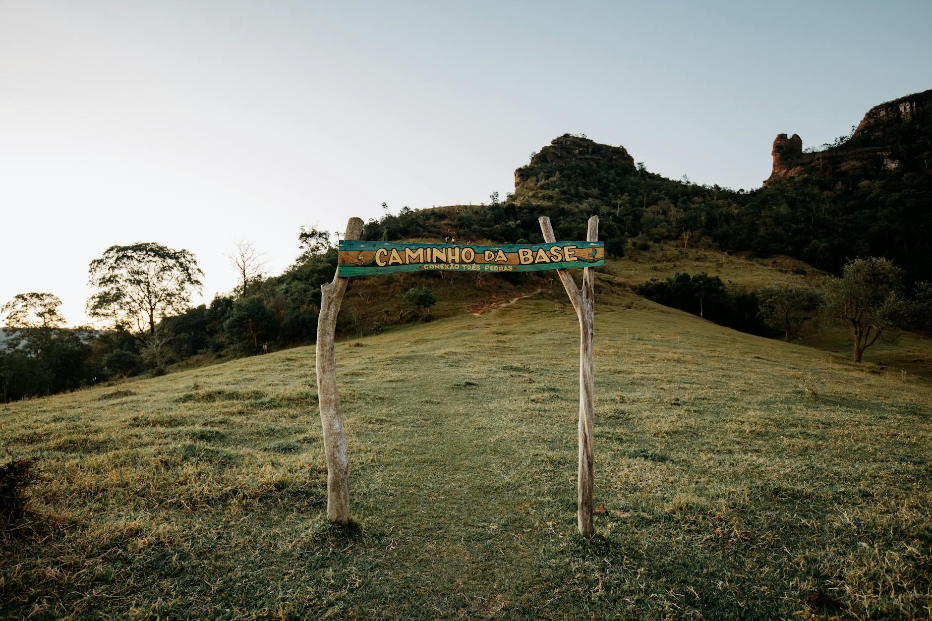 Trail entrance at Caminho da Base amidst scenic Brazilian landscape, lush greenery.