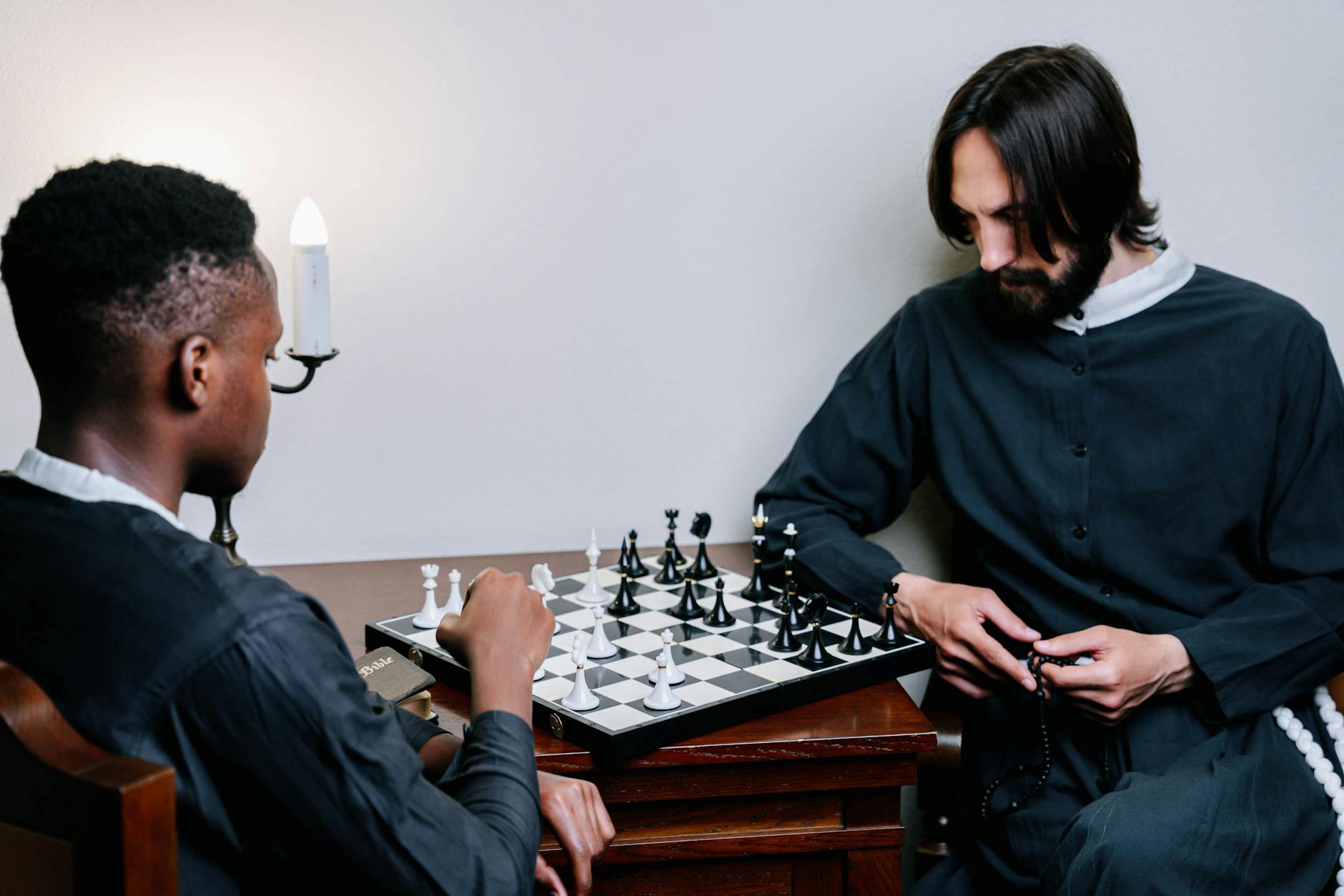 Two men concentrate intensely over a chessboard, playing a strategic game indoors.