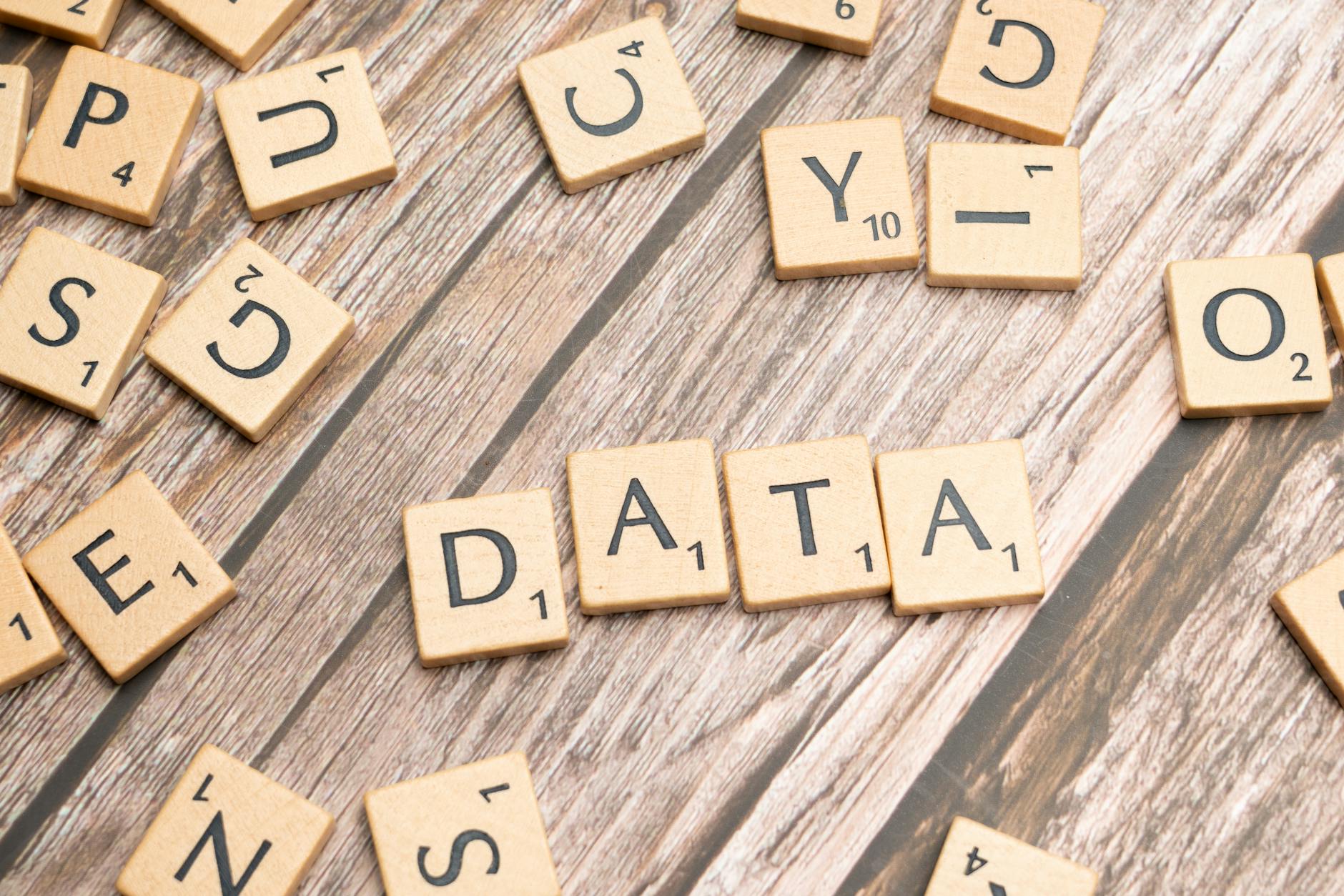 Wooden letter tiles spelling 'DATA' on a wood textured surface, symbolizing data concepts.